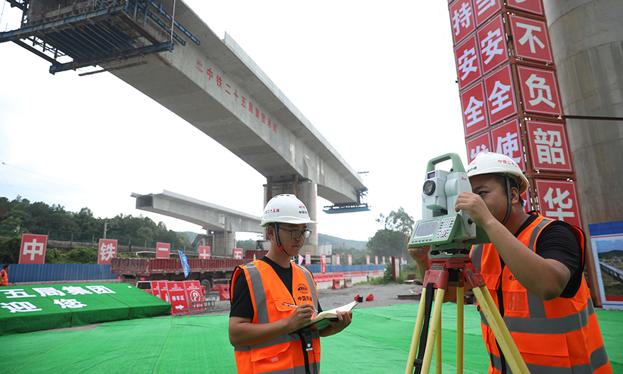 整座桥梁均位于岩溶发育地段，基础施工难度较大，其中15号主墩位于京九铁路路基、排水涵洞与车流量密集的G205国道“夹心地”内，现场施工条件极为有限，一度成为“卡脖子”工程。图为技术人员进行测量。（邓联旭 摄）