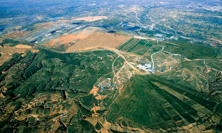 准能矿区排土场，乔灌木林高低错落有致、玉米地、苜蓿地一望无际、成群的牛羊悠然自得、蔬果大棚整齐排列，偶尔有野鸡、野兔穿过，打破排土场的宁静……这些不是构想，而是真真切切呈现在准能集团两矿排土场上的事实。图为复垦绿化鸟瞰图。