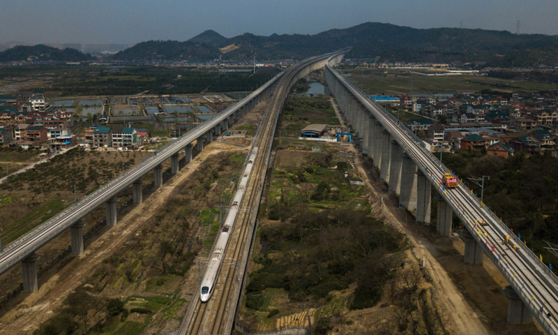 3月12日，中铁四局施工技术人员在传芳特大桥上进行杭黄铁路的铺轨作业，一列高铁从旁边的沪昆客运专线上驶过（无人机拍摄）。（新华社记者 黄宗治 摄）