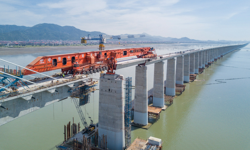 图为7月11日，在新建福厦铁路湄洲湾跨海大桥建设现场，中铁十一局工人协同“昆仑号”千吨级运架一体机架设该线路最后一孔40米箱梁。（新华社记者 宋为伟 摄）