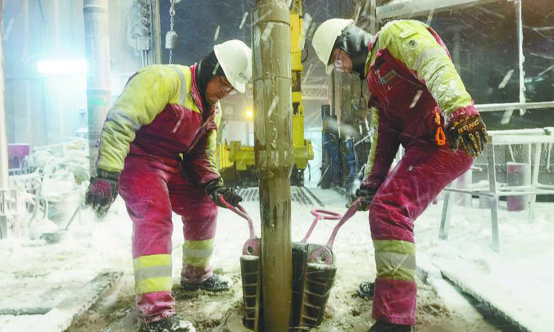 中国海油员工顶风冒雪坚守一线，做好设备防冻、管线防堵和场地防滑工作，确保恶劣天气下钻井生产安全、有序、平稳运行，全力保障能源供应。图为在起下钻作业中，两名钻工冒着风雪合力进行坐卡瓦操作。