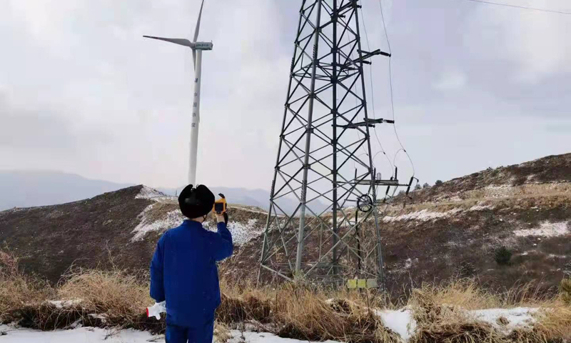 图为华能河北清洁能源分公司涿鹿风电场检修职工用红外测温仪，检查集电线路连接处温度是否正常，确保安全稳定运行。