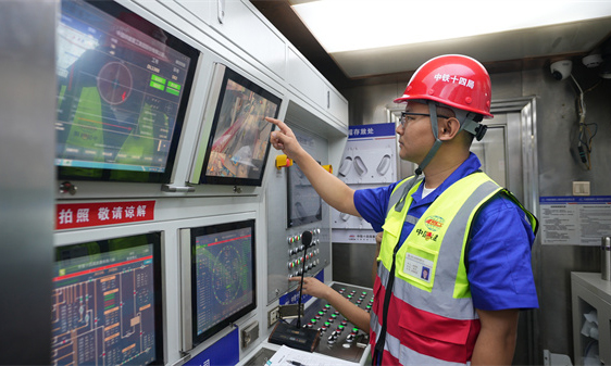 项目建设团队采用高精度北斗卫星定位技术，进行铁路路基安全监测，严格控制现场施工设备的工作半径与站位，确保不对既有线路接触网产生影响。施工期间，项目数字化智慧指挥中心利用测量数据，指导盾构机精准平稳前进，误差控制在毫米级。图为技术人员监控盾构机运行情况。