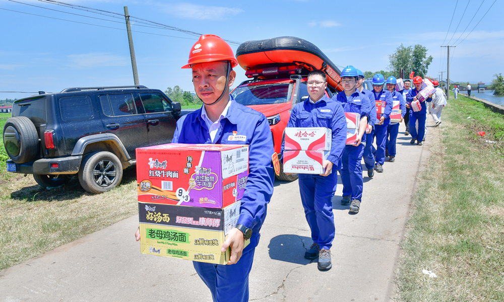 7月6日，国家能源集团湖南岳阳电厂第一时间组织物资驰援团洲垸洞庭湖堤防决口现场。图为电厂驰援人员到达大堤决口现场搬运物资。