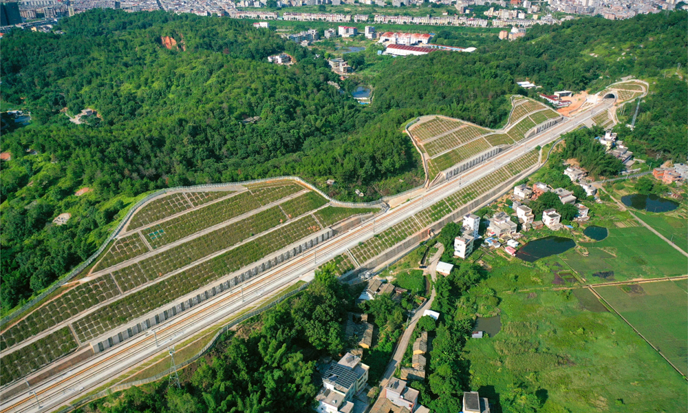 开工建设以来，中国铁建各参建单位克服地质条件复杂、特殊结构多、山区气候多变等诸多难题，保质保量完成了建设任务。全长7377米的下黄田隧道是全线最长隧道，其最大埋深290米，穿越山区多条地质破碎带、岩溶强烈发育带，地下水丰富。施工中，中铁二十五局建设团队采取长隧短打、斜井开挖的方式，多点施工、协同作业，并采用3D全息扫描分析等新型工装工艺和智能化建造技术，为隧道贯通提供了保障。图为龙龙高铁梅龙段路基航拍。