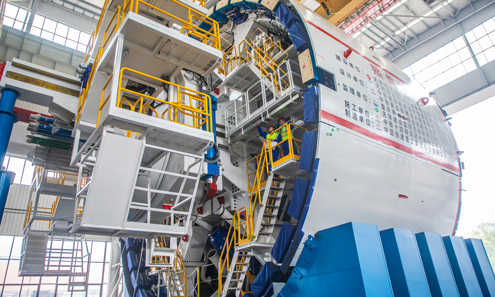 中铁十四局负责锡宜S2线盾构段长10.784公里，将采用2台开挖直径达14.02米的泥水盾构机施工。此次下线的“熙怡号”盾构机需连续下穿太湖湖域段长约6.5公里，面临湖底地质复杂等多重严峻挑战，对盾构机施工的沉降控制、污染防治、风险管控提出极为严格的要求。图为监造人员检查验收盾构机。